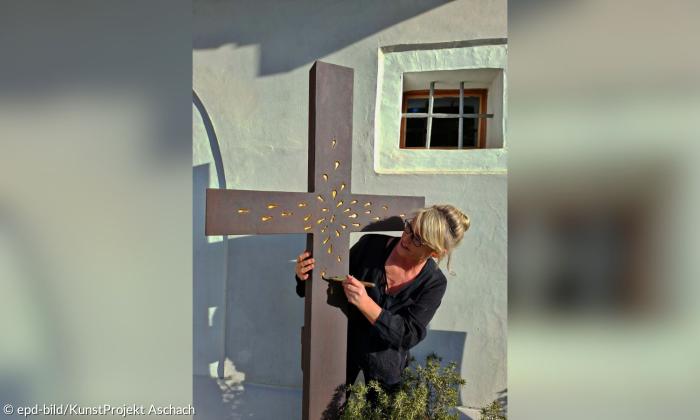 Eine Frau mit einem großen Kreuz, das sie von hinten umfasst