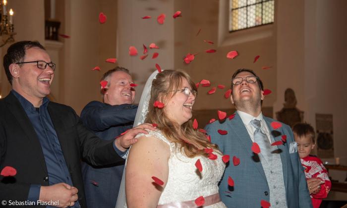 Vier Menschen in einer Kirche, mit Herzchenkonfetti