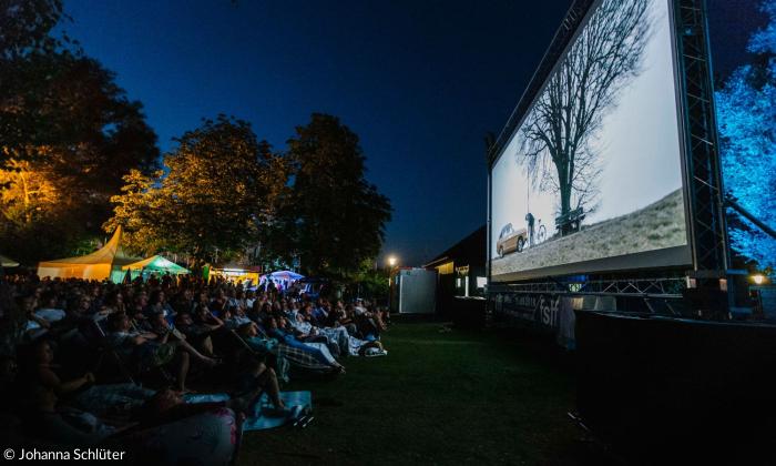Eine Leinwand, davor sitzen Menschen