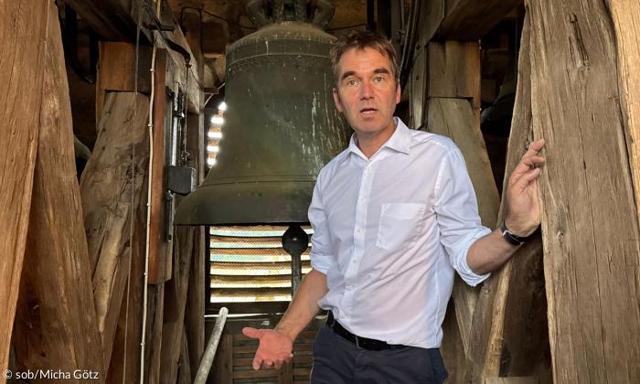 Ein Mann steht vor einer Glocke
