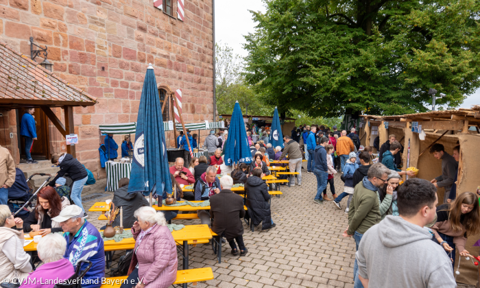 Burgmarktstände und Sitzgarnituren mit Menschen im Innenhof der Burg Wernfels