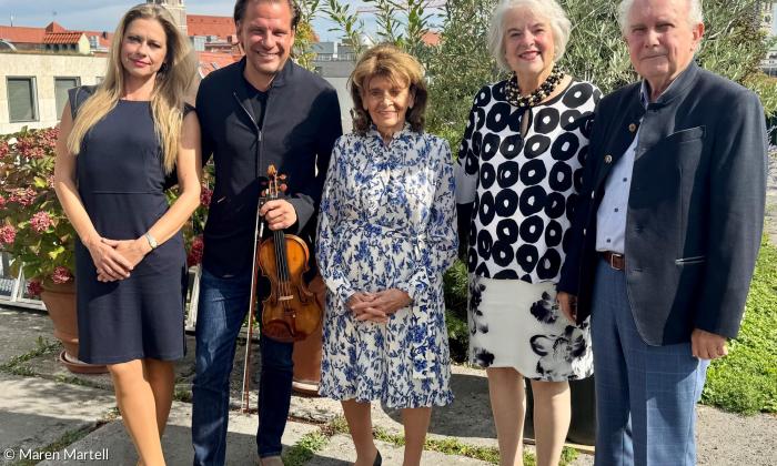 Fünf Personen stehen auf einer Dachterasse, mit Münchner Skyline im Hintergrund. Von links nach rechts: Alexandra Troussova und Kirill Troussov (mit Geige in der Hand), Charlotte Knobloch, Doris Pospischil und Hans-Joachim Scholz.