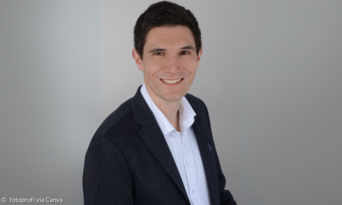 Porträt von Felix Roleder vor grauem Hintergrund.