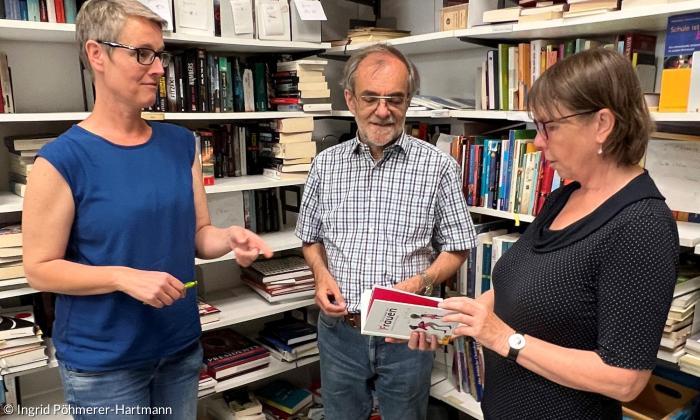 Drei Menschen im Gespräch vor einem Bücherregal