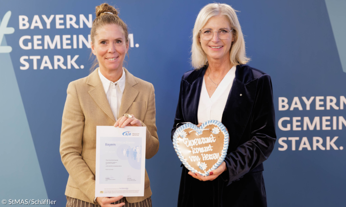 Ilona Schuhmacher (l.), Geschäftsführerin der Evangelischen Jugend in Bayern, wird von Sozialministerin Ulrike Scharf (r.) mit dem Ehrenamtsnachweis Bayern ausgezeichnet.