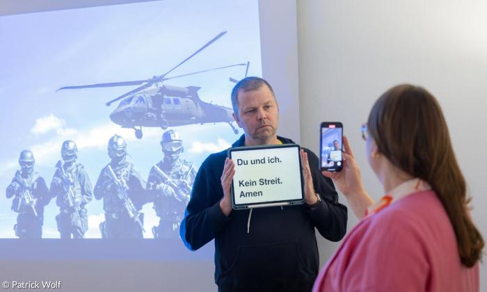 Zwei Leute mit Handy vor einer Leinwand