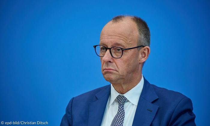 Bundeskanzler Friedrich Merz (CDU) vor blauem Hintergrund