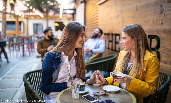 Zwei Frauen sitzen im Café und unterhalten sich.