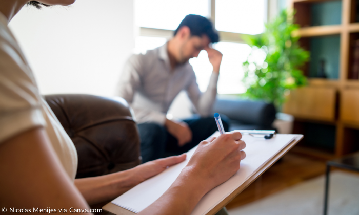 Therapiestunde. Die Therapeutin notiert etwas, der Klient stützt seinen Kopf auf die Hand