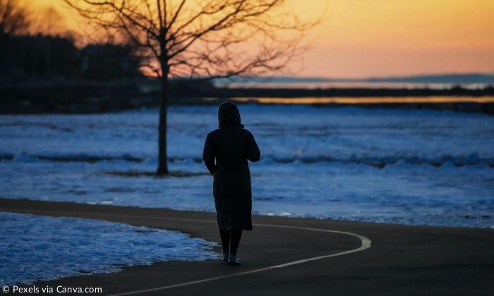 Eine Person steht auf einem Weg, im Abendlicht