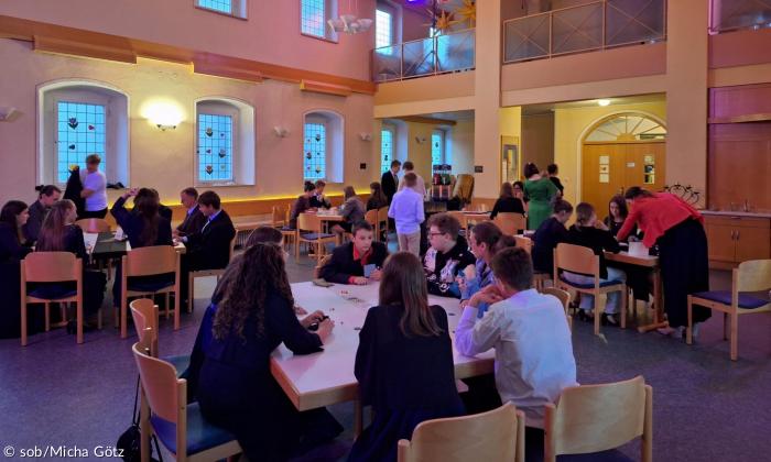 Die Kirche im pink violettem Ton während dem Galaabend. Tisch und Stühle und viele Konfirmanden
