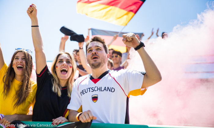 Fans beim Fußball mit Deutschlandfahne und Flagge im Gesicht in Jubellaune