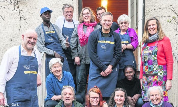Menschen stehen und sitzen in zwei Reihen vor einer Tür