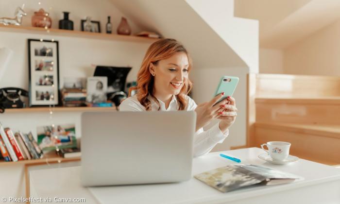 Frau sitzt mit Handy am Rechner