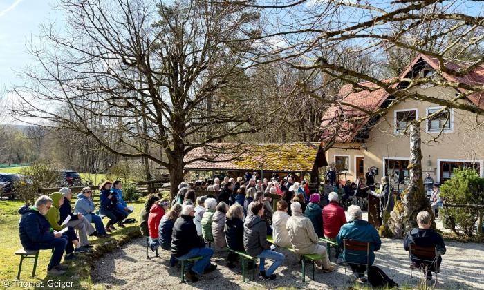 Menschen sitzen vor einem Haus auf Stühlen