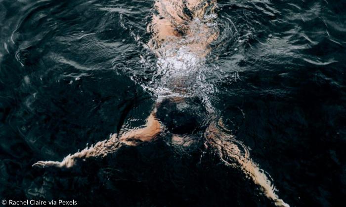 Frau schwimmt unter Wasser in dunklem Ozean