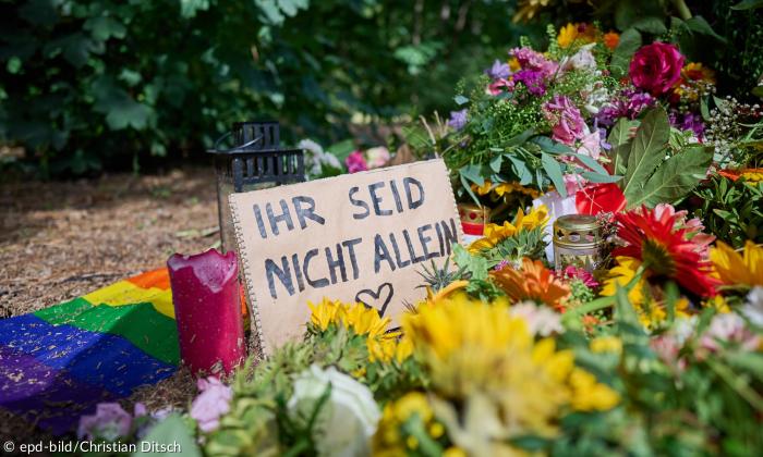 Blumen und ein Schild, auf dem "Ihr seid nicht allein" steht