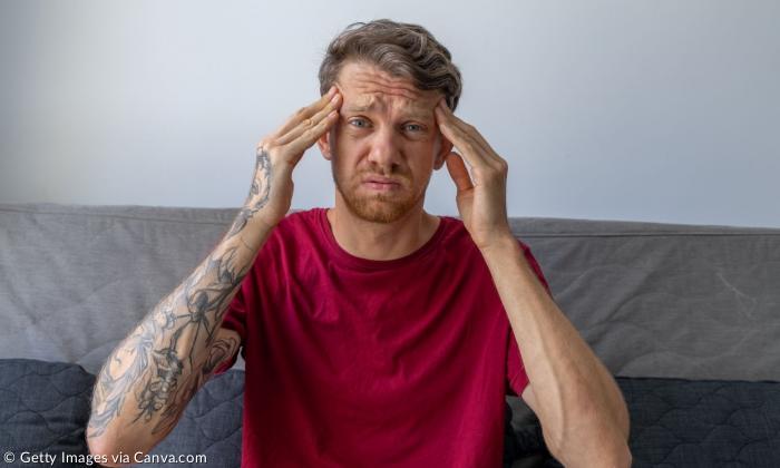 Ein Mann fasst sich mit beiden Händen an die Stirn