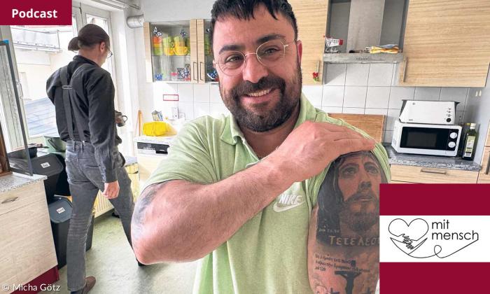 Ein Mann zeigt sein Jesus-Tattoo am Oberarm