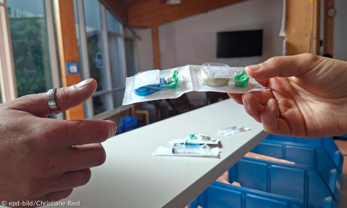 Eine Hand reicht in Plastik verpackte Sachen an eine andere Hand