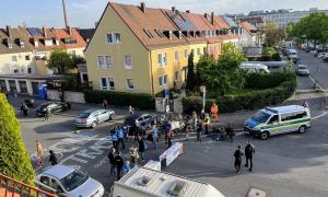 eine Schulstraße, darauf Menschen und ein Polizeiauto