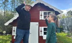 Ein Junge und ein Mann stehen vor einem Gartenhaus und geben sich High Five
