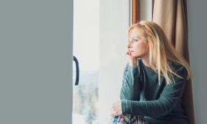 Eine Frau schaut nachdenklich aus dem Fenster