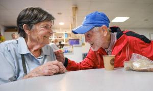 Eine Frau und ein Mann sitzen an einem Tisch, auf dem ein Kaffeebecher steht