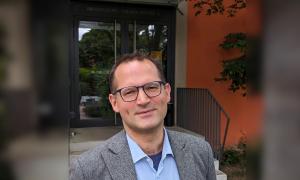 Ein Mann im grauen Sakko und hellblauem Hemd