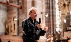 Ein Mann hält ein Mikrofon, er steht in einer Kirche