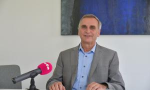 Ein Mann im grauen Sakko und hellblauem Hemd