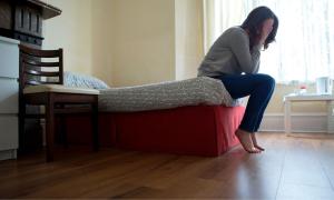 Frau sitzt mit verzweifelter Gestik am Rande des Bettes