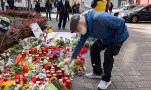 Ein Mann stellt eine Kerze auf, es stehen schon viele Kerzen auf der Straße