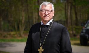 Ein Mann mit grauem Haar und Kreuzkette