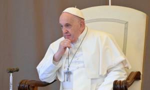 Der Papst sitzt auf einem Stuhl und hält sich nachdenklich die Hand an das Kinn