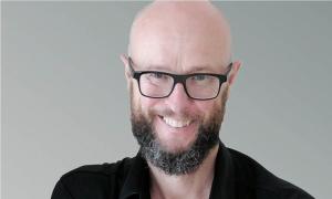 Ein Mann mit Brille und Bart lächelt