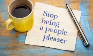 Ein Notizzettel mit der Aufschrift "Stop being a people pleaser" neben einer Kaffeetasse