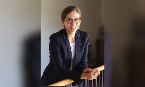 Eine Frau im dunklen Blazer lehnt sich über ein Geländer