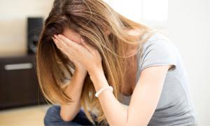 Eine Frau verbirgt die Hände im Gesicht