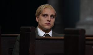 Ein Mann mit blonden Haaren sitzt auf einer Kirchenbank