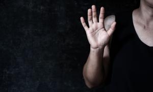 Eine Frau hebt abwehrend die Hand