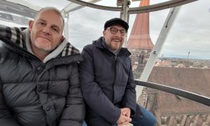 Zwei Männer sitzen warm angezogen in einer Riesenrad-Gondel