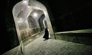 Eine ganz in schwarz verschleierte Frau geht durch einen orientalischen Gang