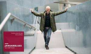 Ein Mann mit Jacke lehnt sich an ein Geländer