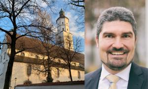 Eine Kirche und ein Mann mit grauen, kurzen Haaren in Anzug und Krawatte