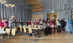 Menschen in bunten Kostümen ziehen in einer Polonaise durch einen Raum