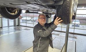 Ein Mann steht unter einem aufgebockten Auto
