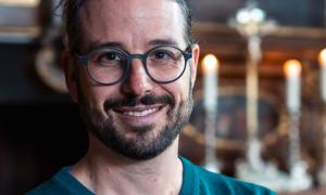 Ein Mann mit runder Brille lächelt in die Kamera