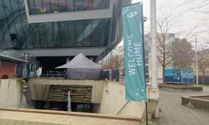 Ein Eingang mit Betontreppen in München, daneben eine Willkommensfahne