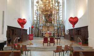 Eine Kirche, in der rote herzförmige Luftballons schweben